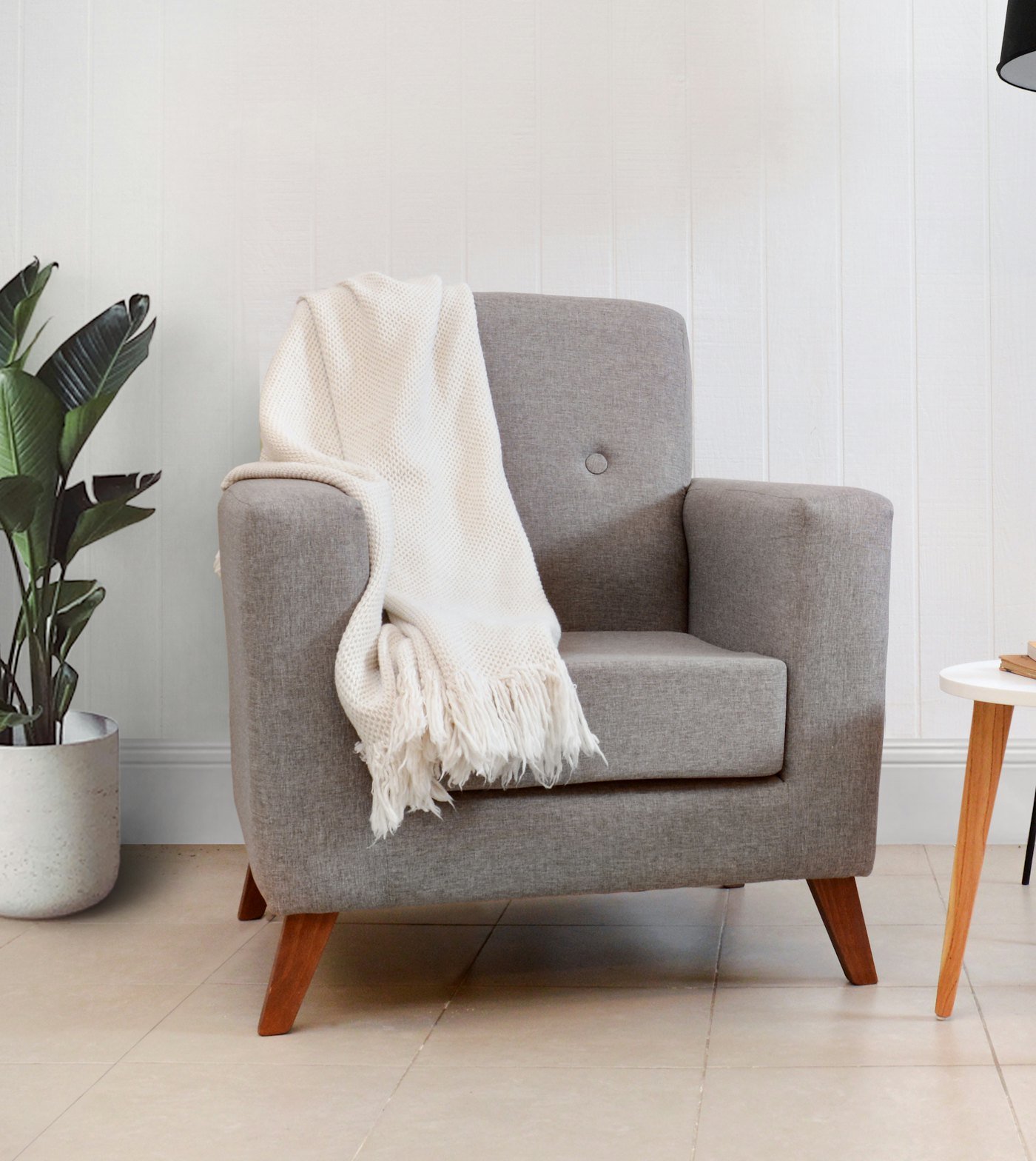 A quiet counselling room with a grey armchair and a soft throw
